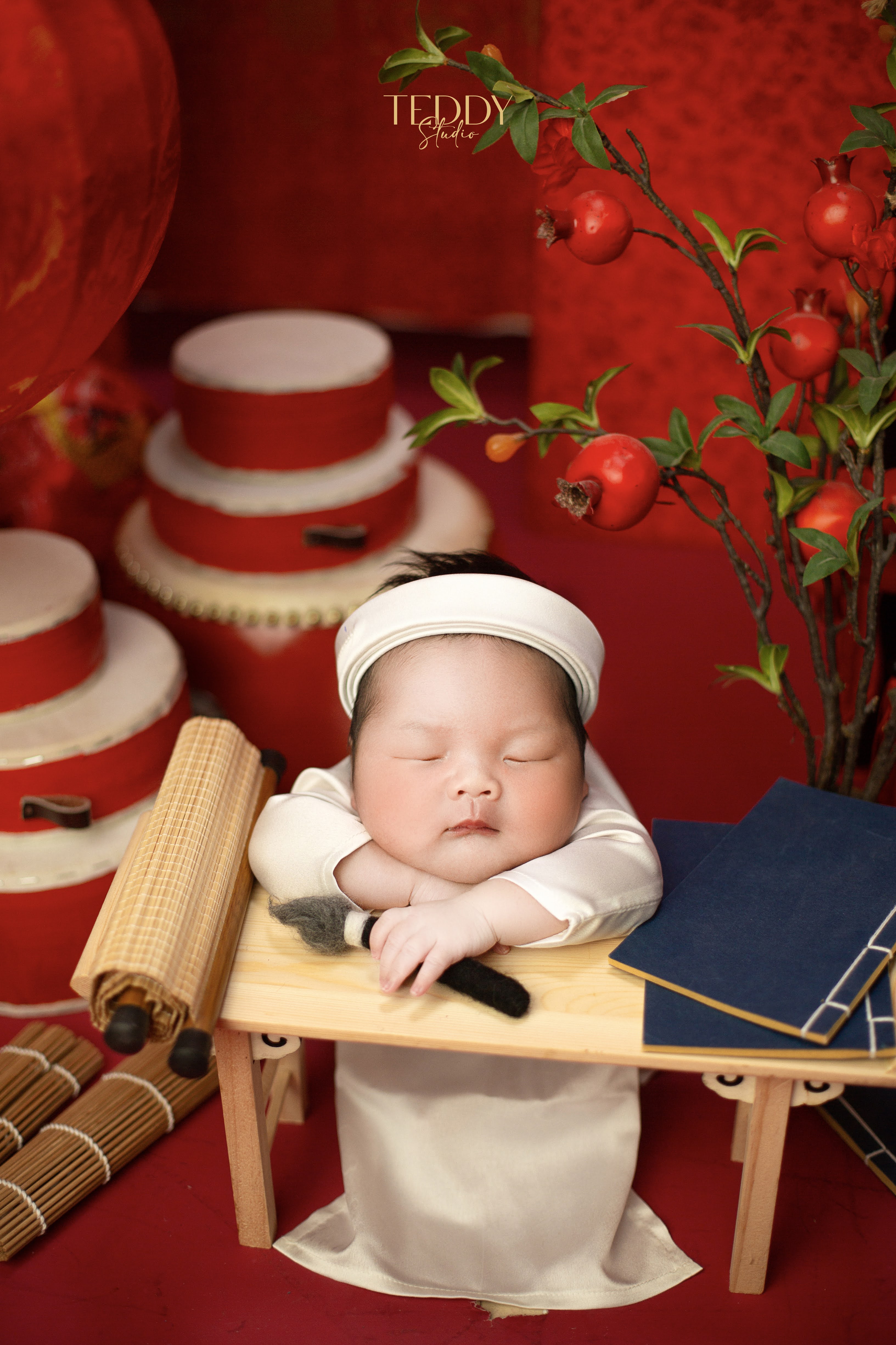 Chụp ảnh newborn bé thầy thư nhỏ nền đỏ sách cổ trống tại Teddy Studio